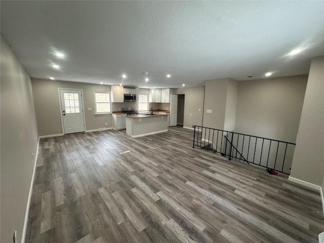 unfurnished living room featuring sink, light hardwood / wood-style flooring, and a textured ceiling