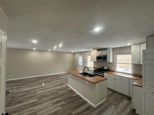 kitchen featuring sink, butcher block counters, white cabinetry, stainless steel appliances, and a kitchen island