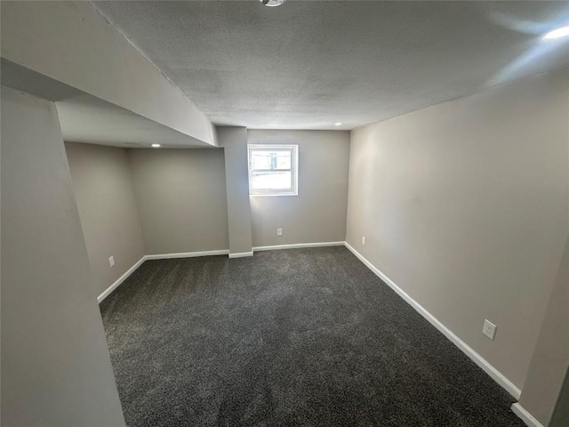 basement with a textured ceiling and dark colored carpet