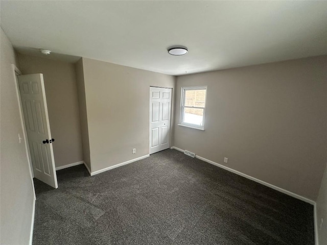 unfurnished bedroom with a closet and dark colored carpet