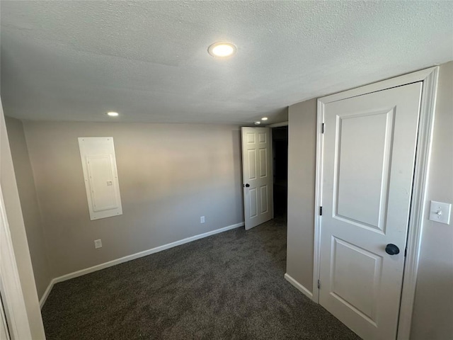 interior space with dark carpet, electric panel, and a textured ceiling