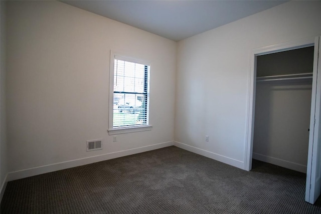 unfurnished bedroom featuring a closet and dark carpet