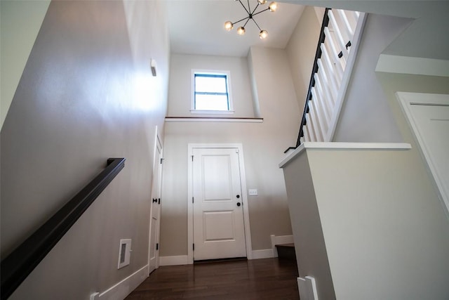 stairs with wood-type flooring and an inviting chandelier