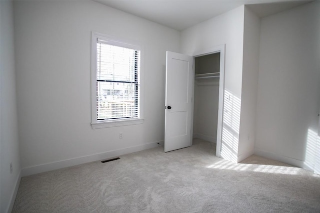 unfurnished bedroom featuring light carpet and a closet