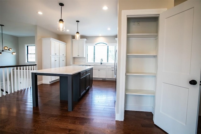 kitchen with a healthy amount of sunlight, white cabinetry, a center island, and hanging light fixtures