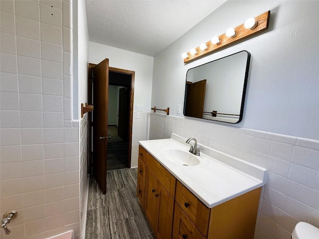 31050 US Highway 322, Cochranton, PA 16314 - bathroom with tile walls, vanity, a textured ceiling, wood finished floors, and a wainscoted wall