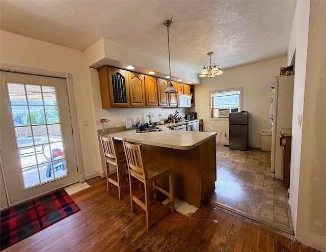 10537 Franklin Pike, Meadville, PA 16335 - kitchen with white appliances, a textured ceiling, brown cabinetry, a peninsula, and a chandelier