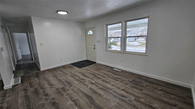 foyer entrance with dark wood-type flooring and a textured ceiling