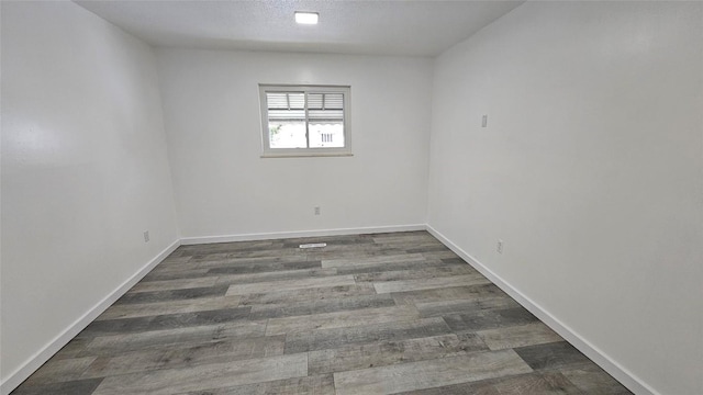 empty room featuring dark hardwood / wood-style floors and a textured ceiling