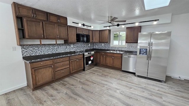 kitchen featuring appliances with stainless steel finishes, sink, light wood-type flooring, and decorative backsplash