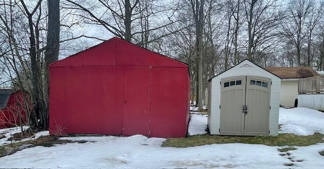 snow covered structure featuring an outbuilding and a storage shed