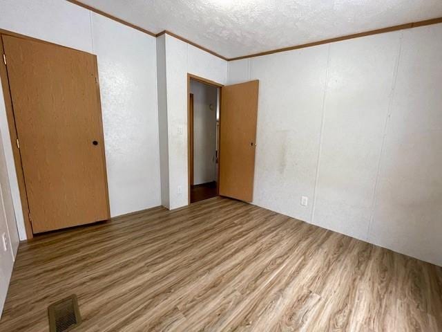 spare room featuring visible vents, crown molding, a textured ceiling, and wood finished floors