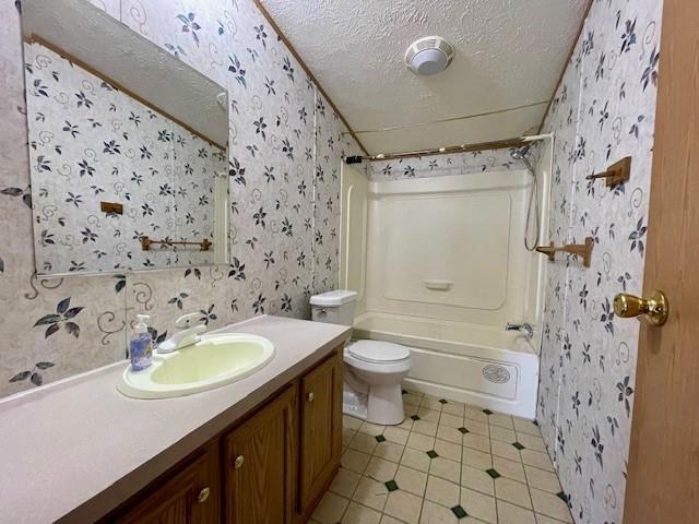 bathroom with toilet, wallpapered walls, a textured ceiling, and vanity