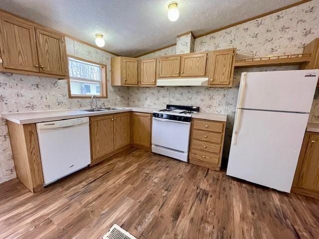 kitchen with a textured ceiling, white appliances, wood finished floors, vaulted ceiling, and wallpapered walls