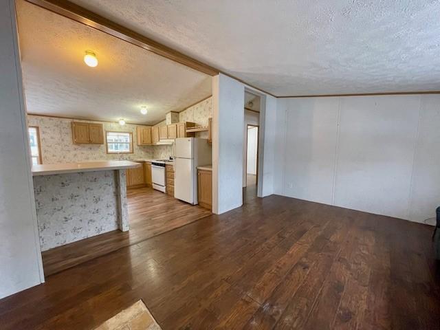 kitchen featuring lofted ceiling, light countertops, white appliances, and dark wood-type flooring