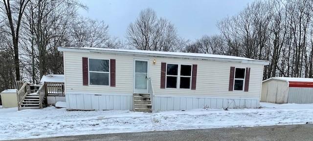 manufactured / mobile home featuring an outbuilding, a storage shed, a wooden deck, and entry steps