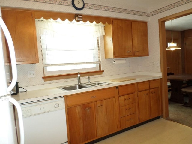 kitchen featuring sink, white appliances, and decorative light fixtures