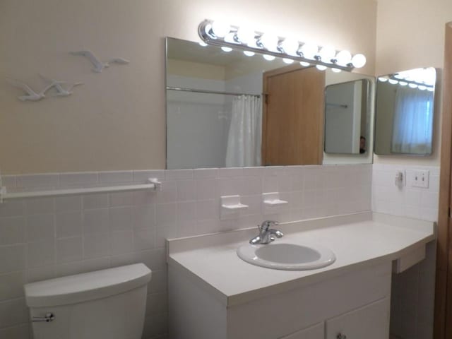 bathroom with vanity, tile walls, walk in shower, and toilet