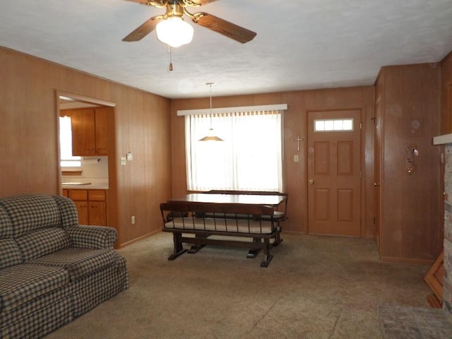 interior space featuring ceiling fan, light carpet, and wooden walls