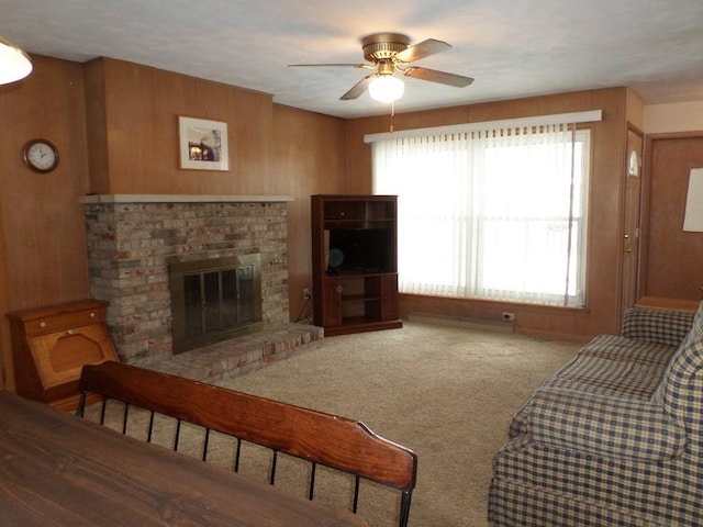 living room featuring a brick fireplace, carpet floors, ceiling fan, and wood walls