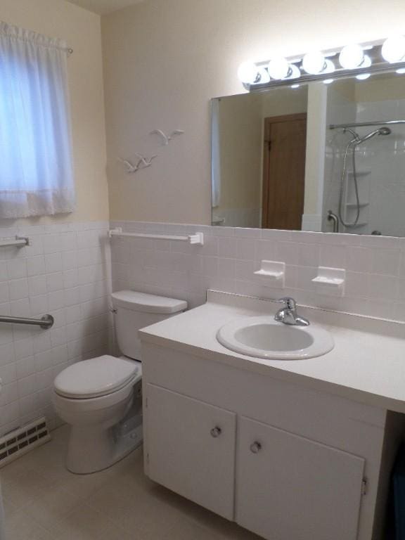 bathroom featuring tile patterned flooring, tile walls, vanity, a shower, and toilet