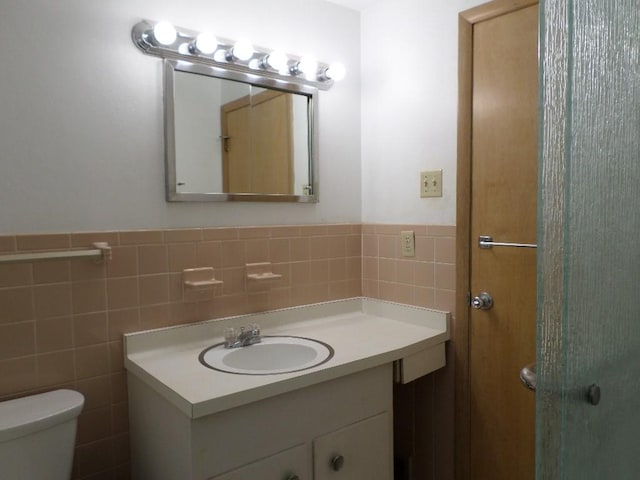 bathroom with vanity, toilet, and tile walls