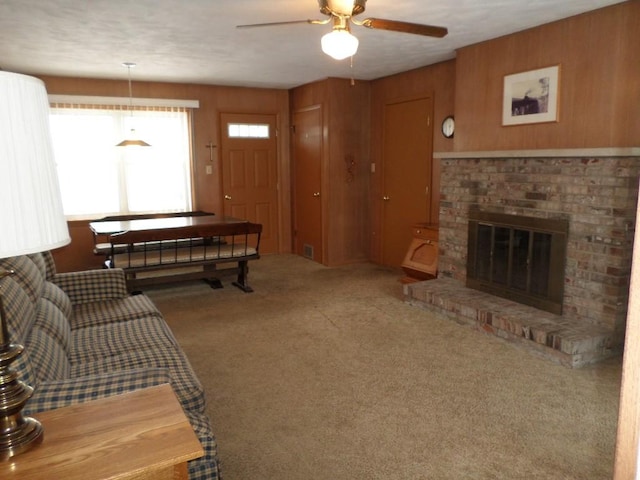 living room with a fireplace, wooden walls, ceiling fan, and carpet flooring