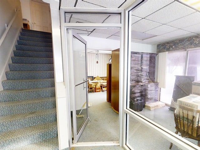 stairs with carpet floors and a paneled ceiling