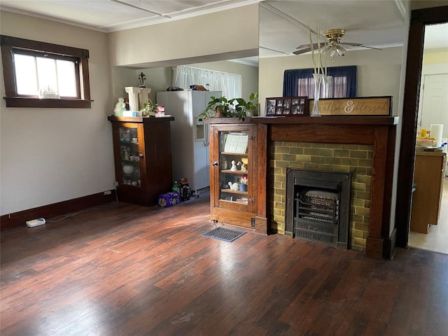 living room featuring a fireplace, ceiling fan, crown molding, baseboards, and wood finished floors
