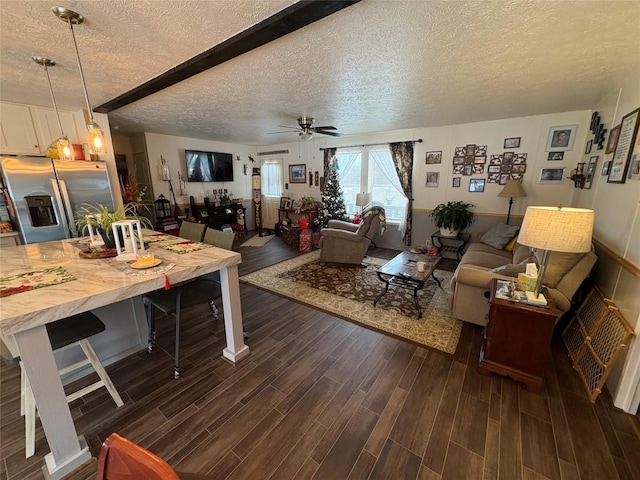 living room featuring ceiling fan, beamed ceiling, and a textured ceiling