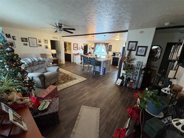 living room featuring ceiling fan, dark wood-type flooring, and a textured ceiling