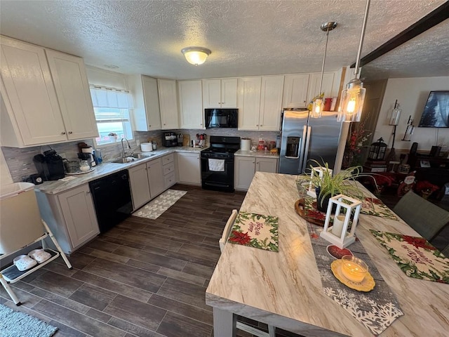 kitchen featuring black appliances, pendant lighting, white cabinetry, and sink