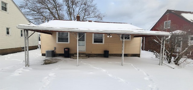 snow covered back of property with central AC