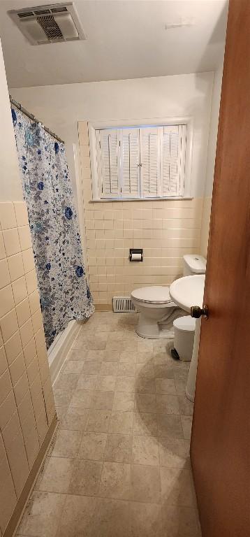 bathroom featuring a shower with curtain, tile walls, and toilet