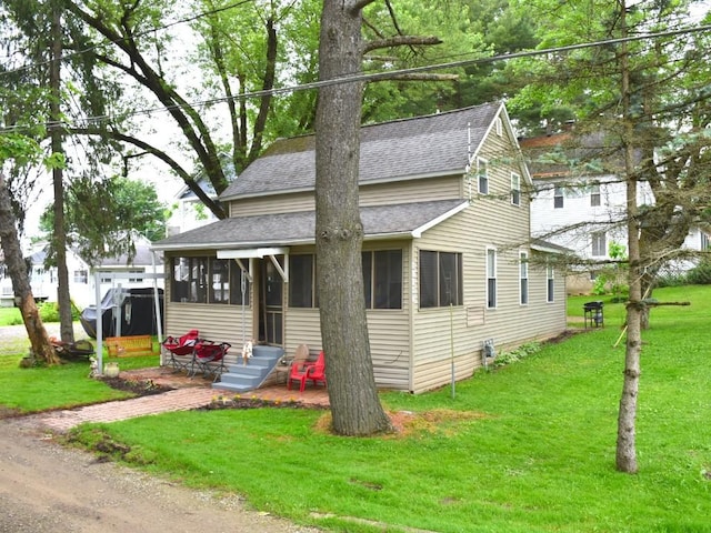 10987 Henry St, Conneaut Lake, PA 16316 - view of front of house with roof with shingles, a sunroom, and a front lawn