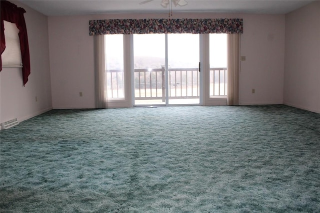 unfurnished room with plenty of natural light, ceiling fan, and carpet floors