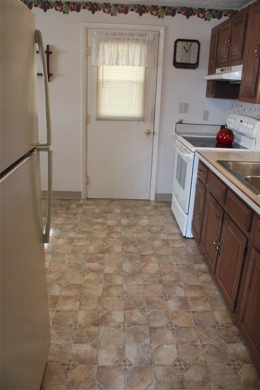 kitchen featuring electric stove, sink, and fridge