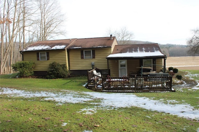 snow covered house with a yard and a deck