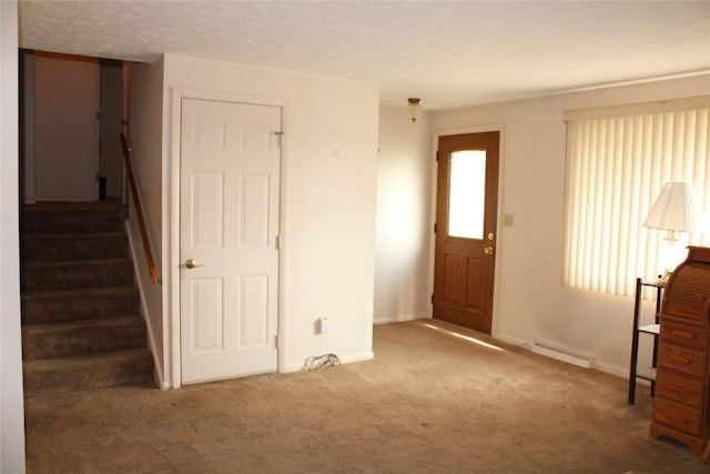 carpeted foyer entrance featuring a textured ceiling