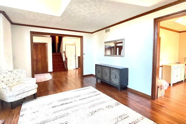 living area featuring visible vents, wood finished floors, crown molding, baseboards, and stairs