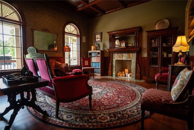 living area with hardwood / wood-style floors, beam ceiling, a premium fireplace, and coffered ceiling