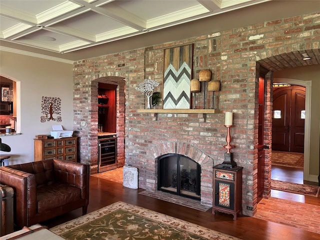 living room featuring beam ceiling, beverage cooler, coffered ceiling, crown molding, and hardwood / wood-style flooring