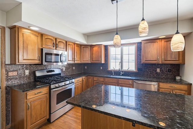 3706 Harbor Ridge Trl, Erie, PA 16510 - kitchen with stainless steel appliances, a sink, light wood-type flooring, dark stone countertops, and brown cabinetry