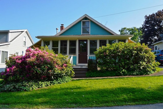 105 Hickory St, Edinboro, PA 16412 - bungalow-style home with a chimney, a front lawn, and a sunroom