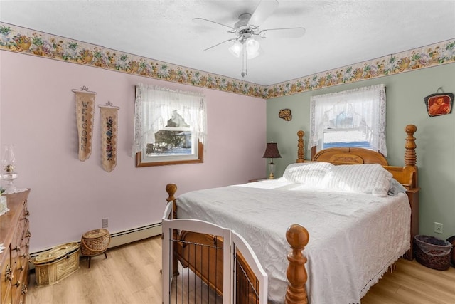 bedroom featuring baseboard heating, ceiling fan, a textured ceiling, and light wood-type flooring