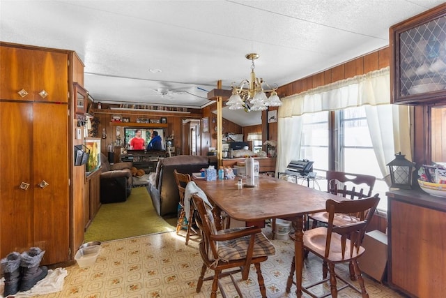 dining space featuring an inviting chandelier, light carpet, a textured ceiling, and wood walls