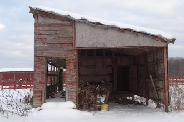 snow covered structure with an outbuilding