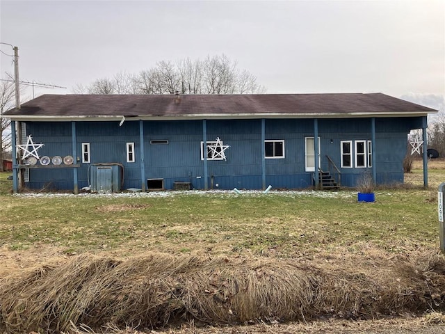 rear view of property featuring entry steps and a lawn