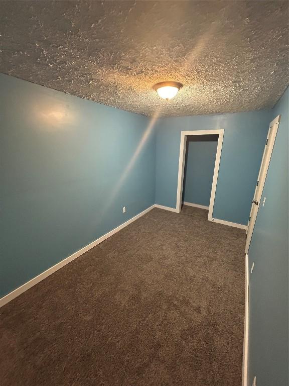 carpeted empty room with a textured ceiling