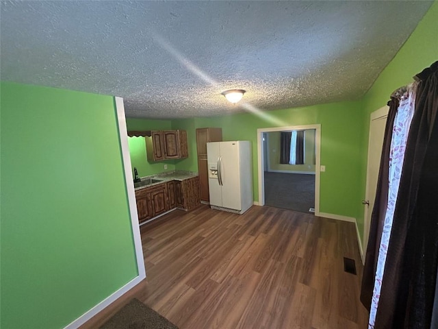 kitchen featuring dark hardwood / wood-style floors, sink, white refrigerator with ice dispenser, and a textured ceiling